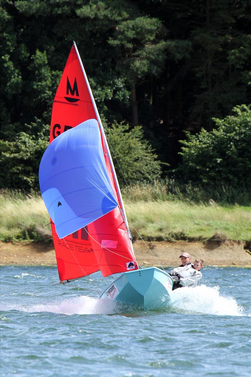 Mirror dinghy sailing towards the camera planing on a reach with spinnaker up