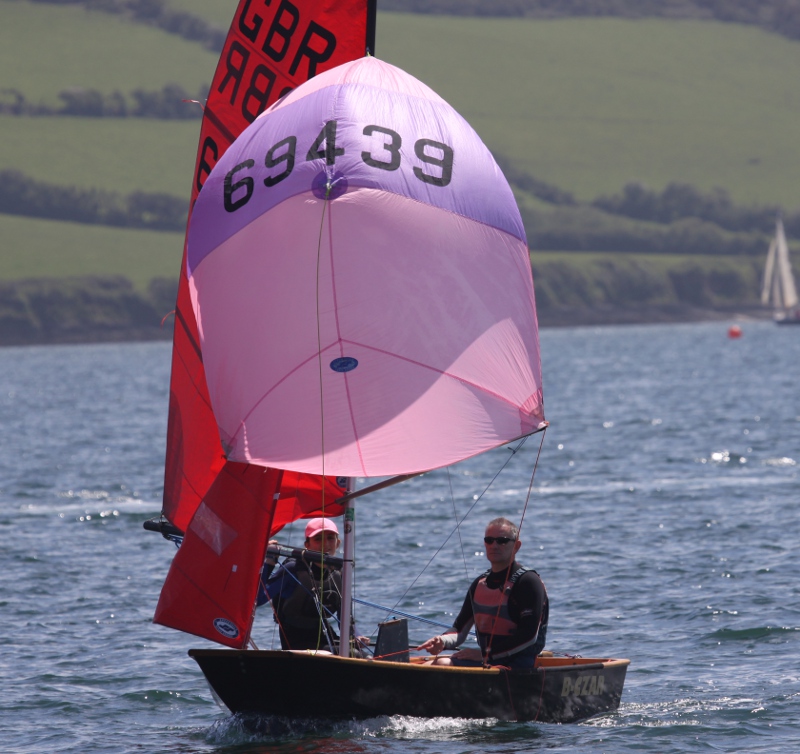 Black wooden Mirror dinghy 'B-Czar' running with pink and purple spinnaker on a sunny day