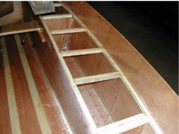 Partly built wooden Mirror dinghy showing the stringer, carlin and beams which will support the side deck