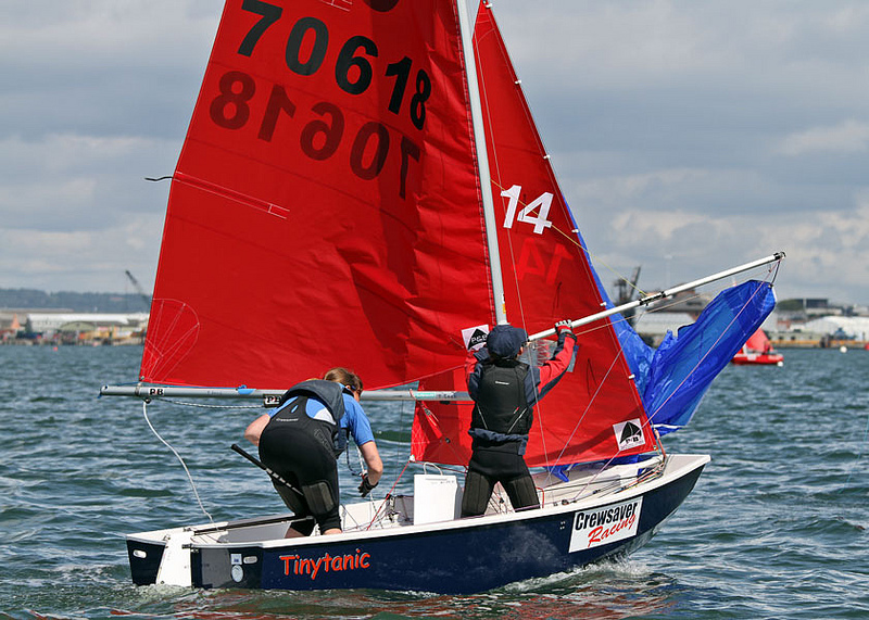 Mirror dinghy with helm hoisting the spinnaker and crew pushing out the pole