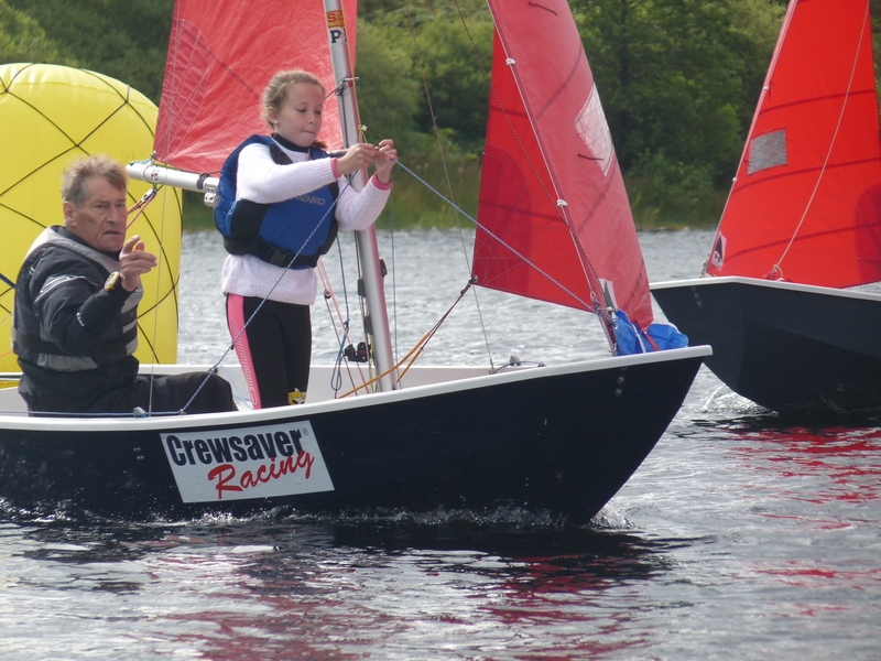 A Mirror dinghy rounding the windward mark with crew standing up cliping guy into pole end