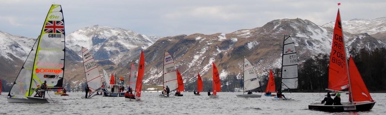 Boats getting ready for a start with snow on the hills in the background