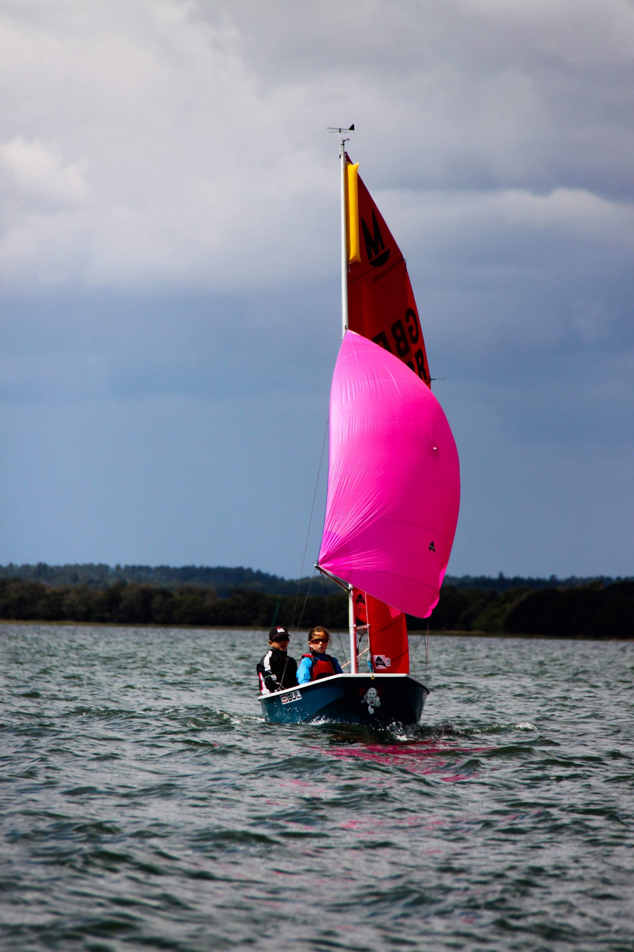 A Mirror racing with spinnaker set sailing towards the camera