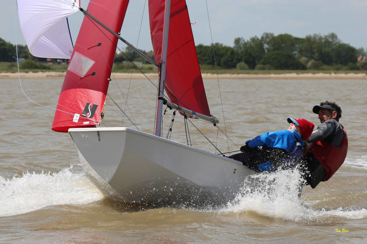 A Father and daughter racing a Mirror dinghy on a beam reach fully powered up with spinnaker set