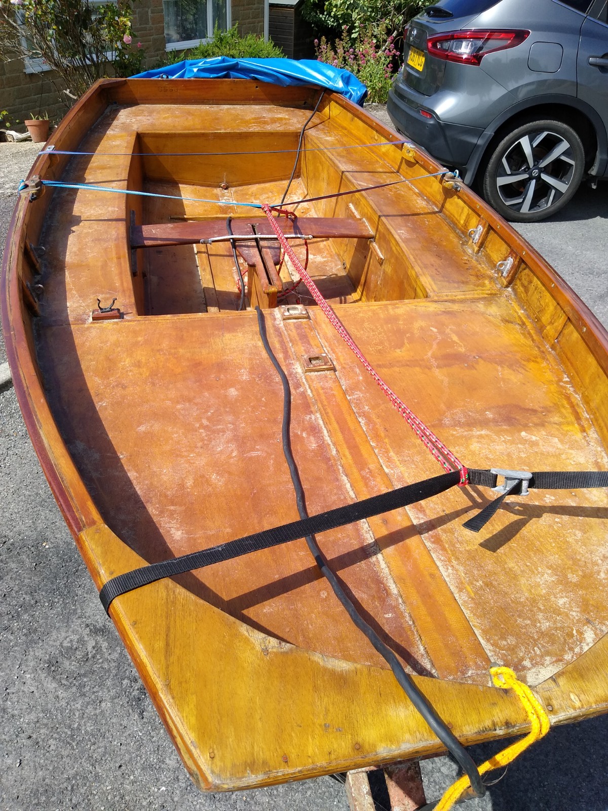 A wooden Mirror dinghy hull, unrigged, on a driveway