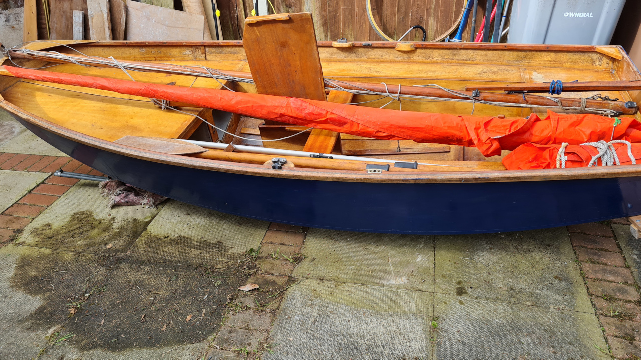 A blue wooden Mirror dinghy resting on a driveway