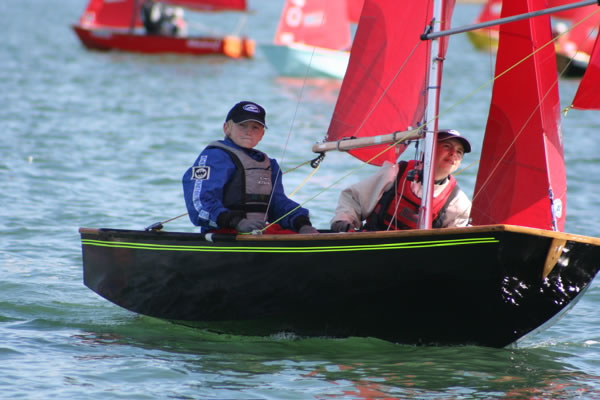 A black wooden Mirror, with green stripe under the gunwale, racing to windward