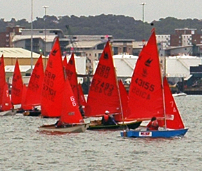 A black gaff rigged Mirror racing to windward in the middle of a fleet of Mirrors