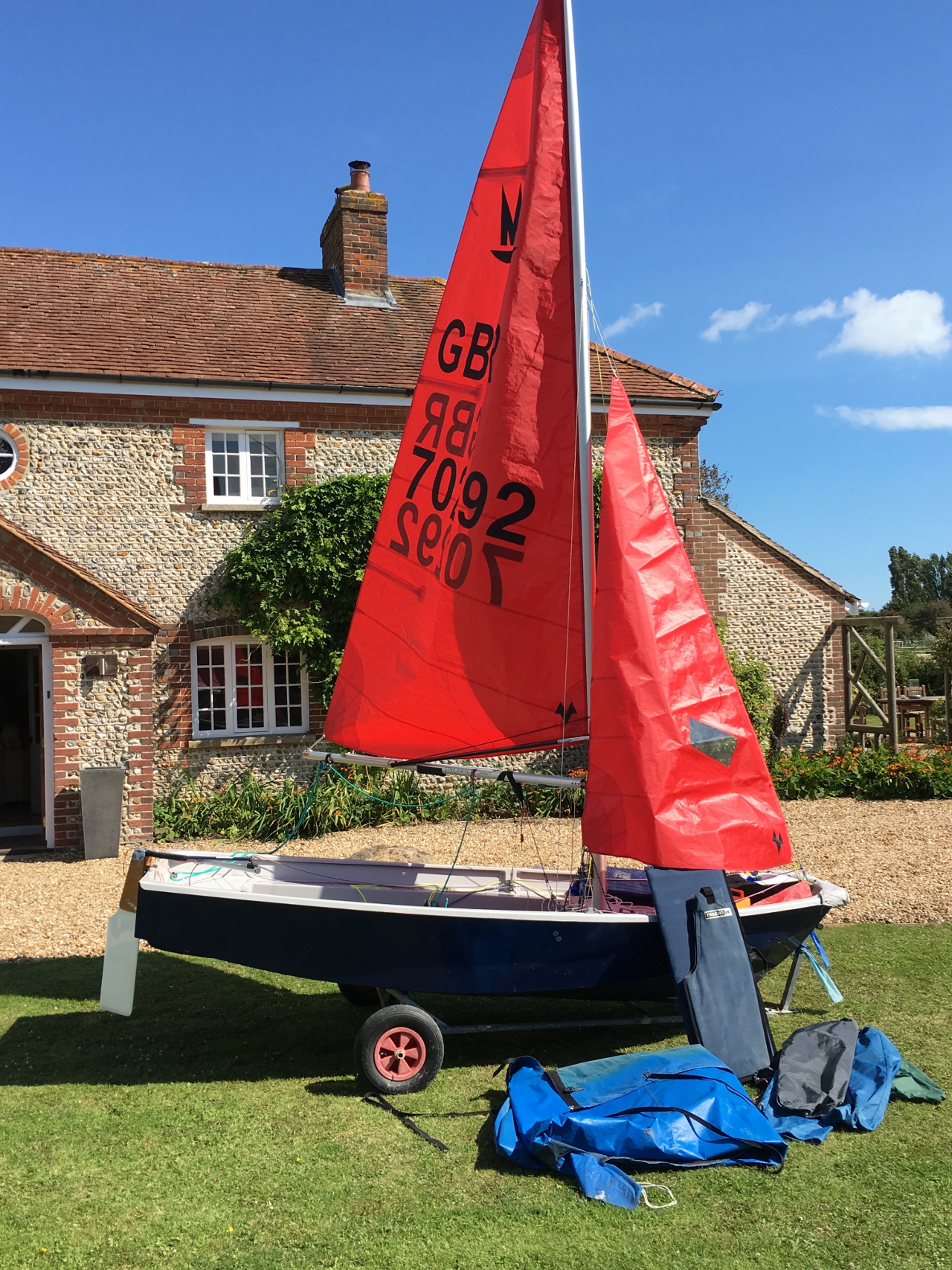 A Mirror dinghy rigged  up outside a house