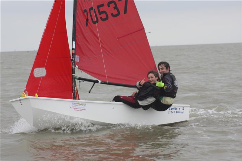 A white GRP Mirror dinghy sailing to windward with helm & crew hiking hard and giving a 'thumbs up' to the camera