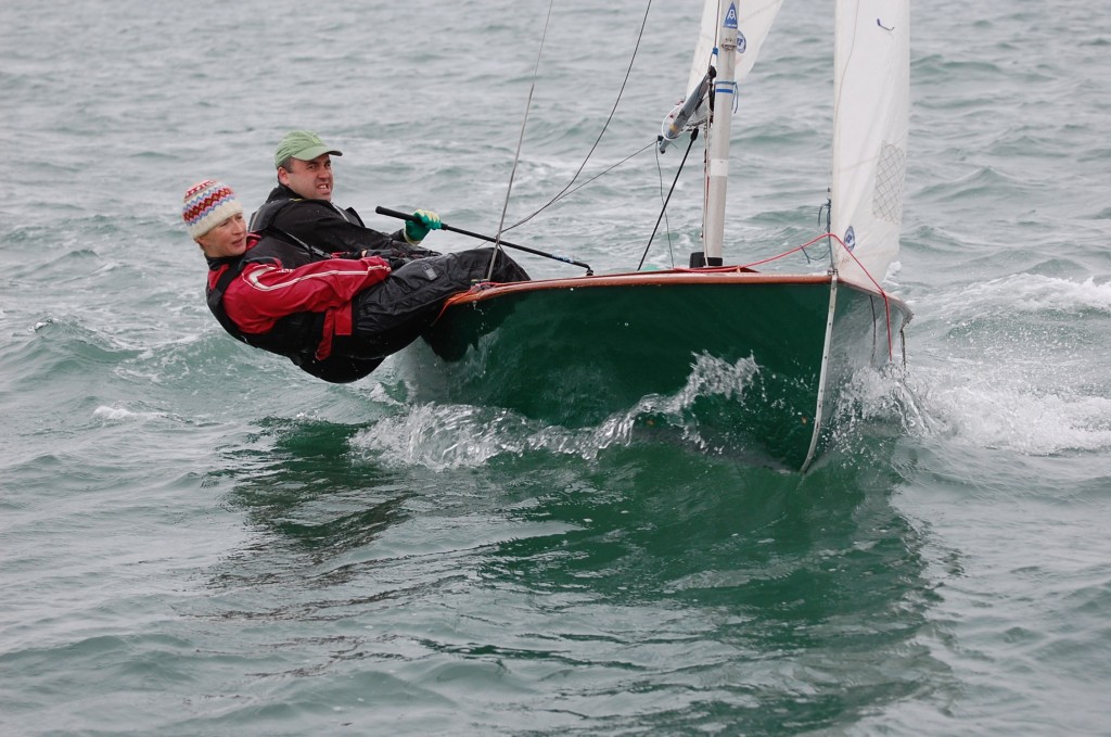 Green GP14 dinghy being sailed to windward by a man and a woman